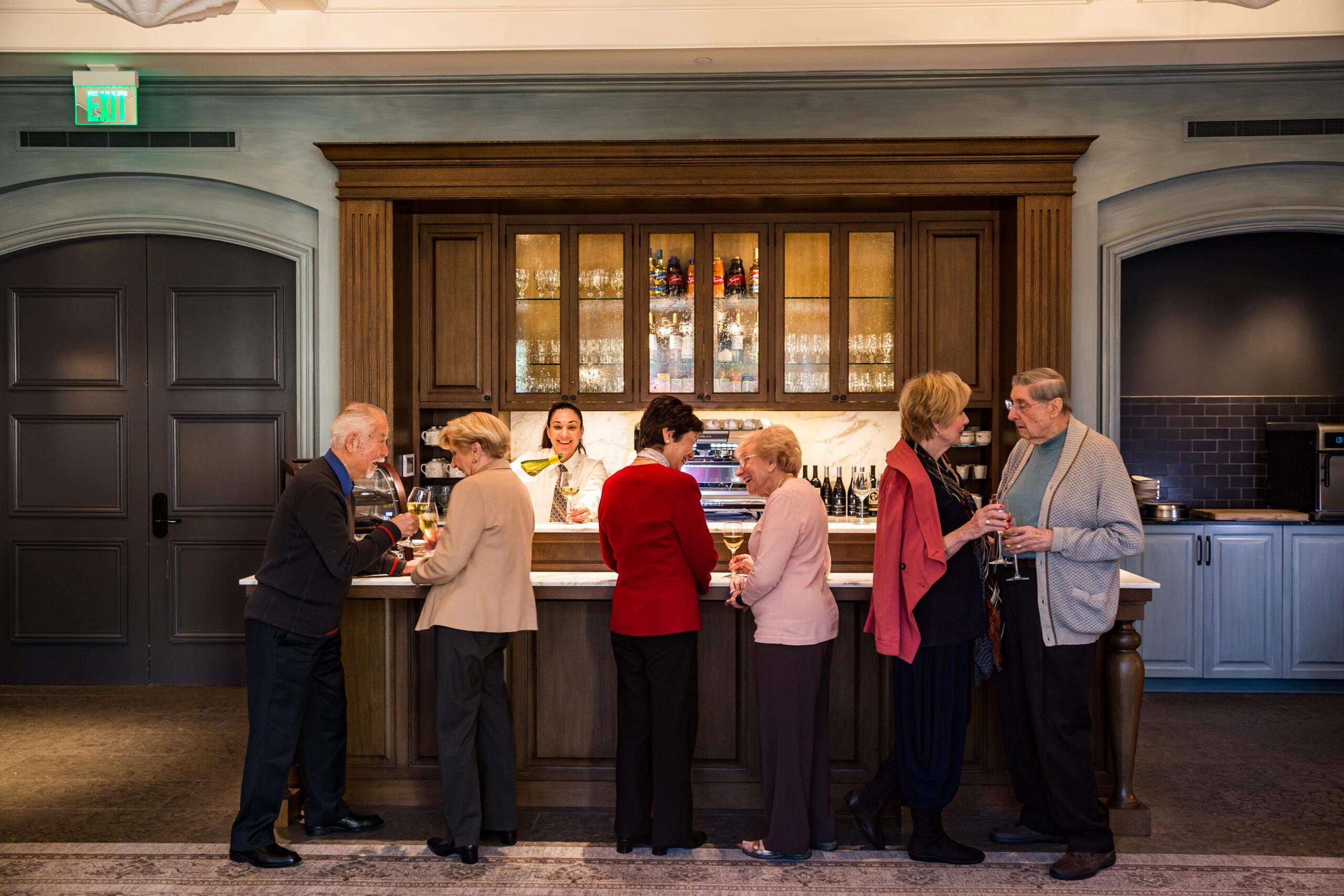 Seniors talk and laugh over drinks at a bar