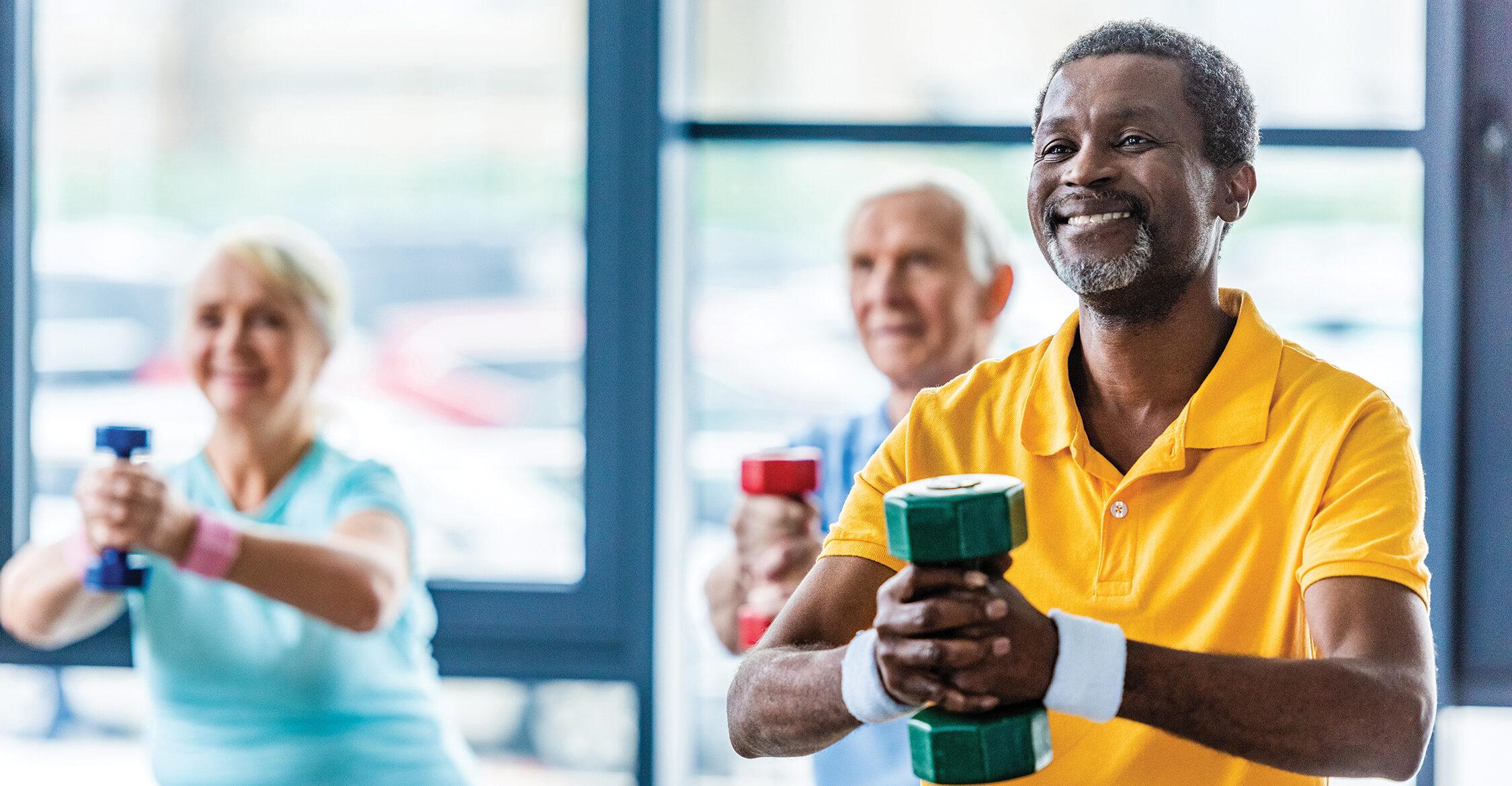 African-american sportsman and his friends exercising with dumbbells at gym