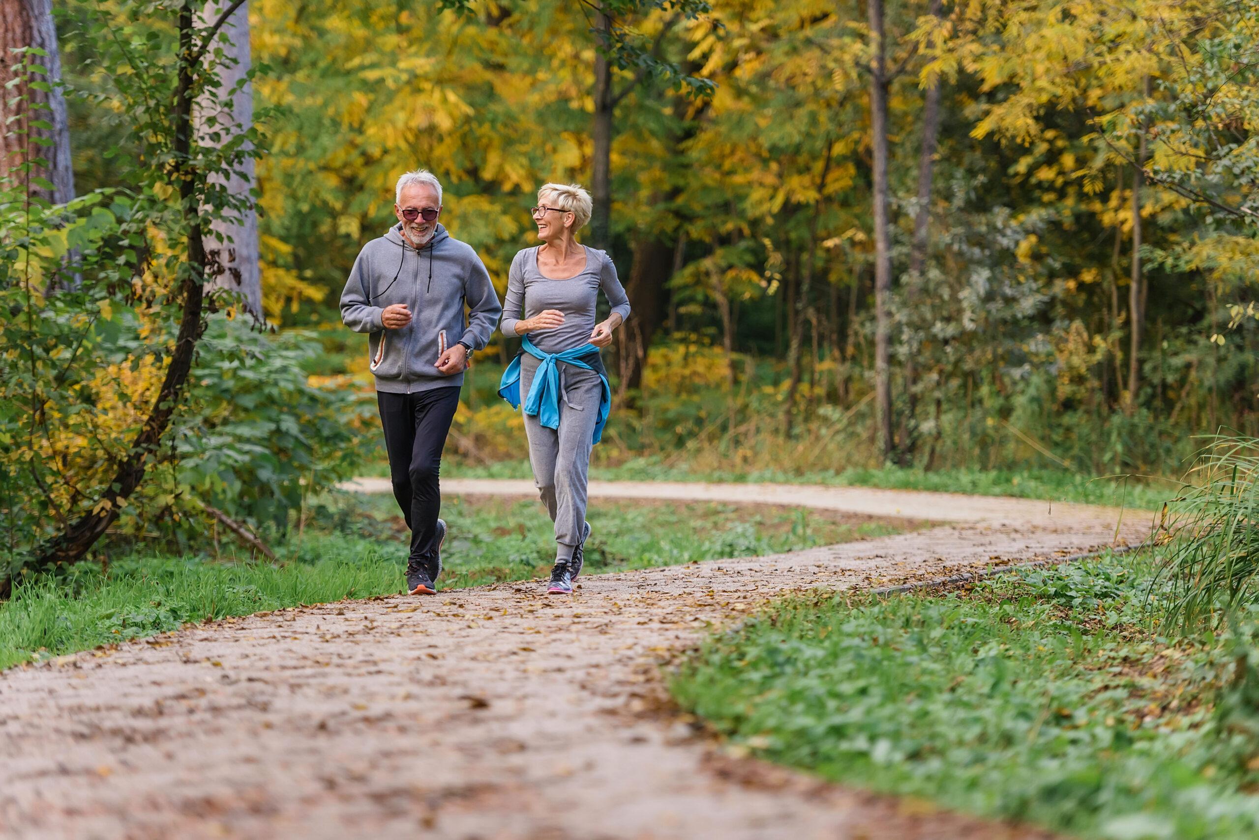 Cheerful active senior couple jogging in the park.