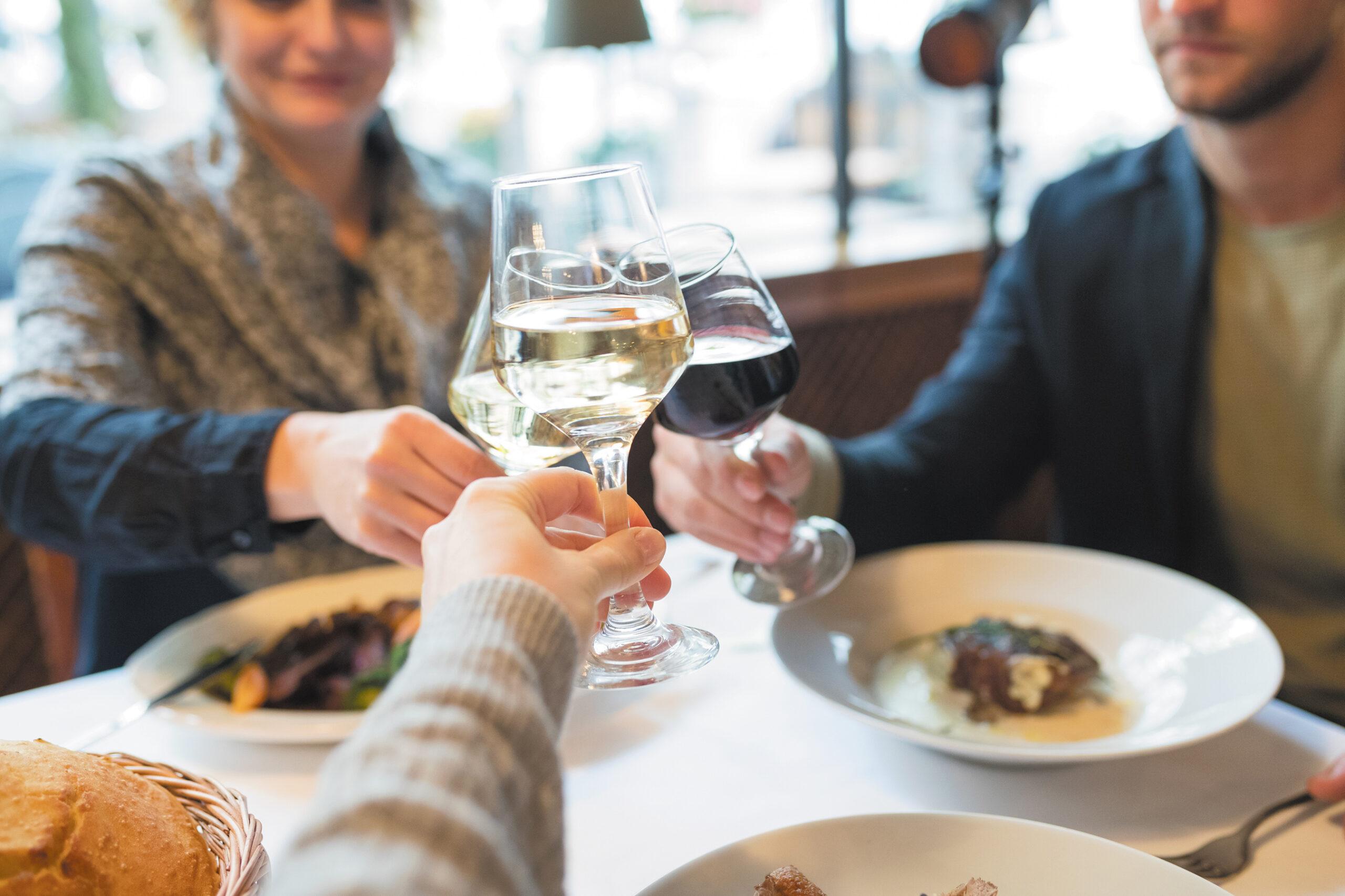 A group of friends toasts wine glasses